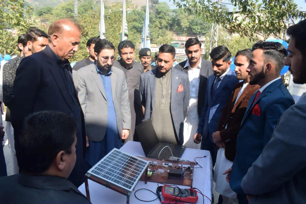 A group of men standing around a table with a solar panel
Description automatically generated